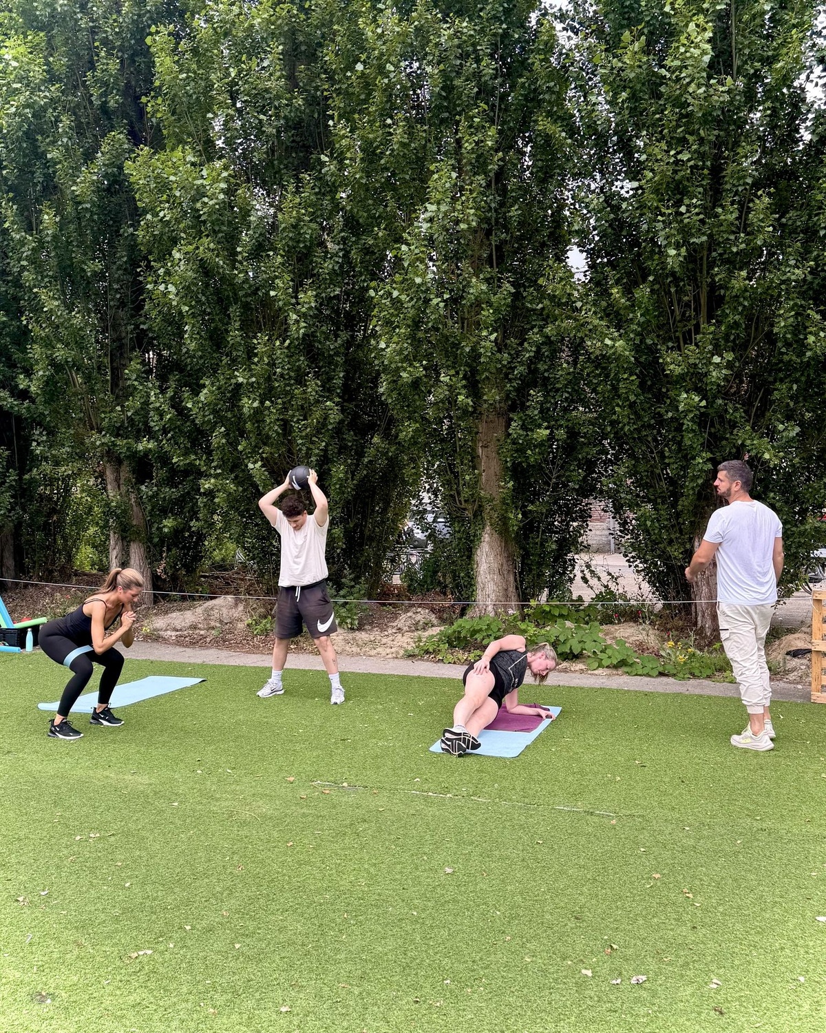 Coach Karel kijkt mee naar de houding tijdens een outdoor groepsworkout