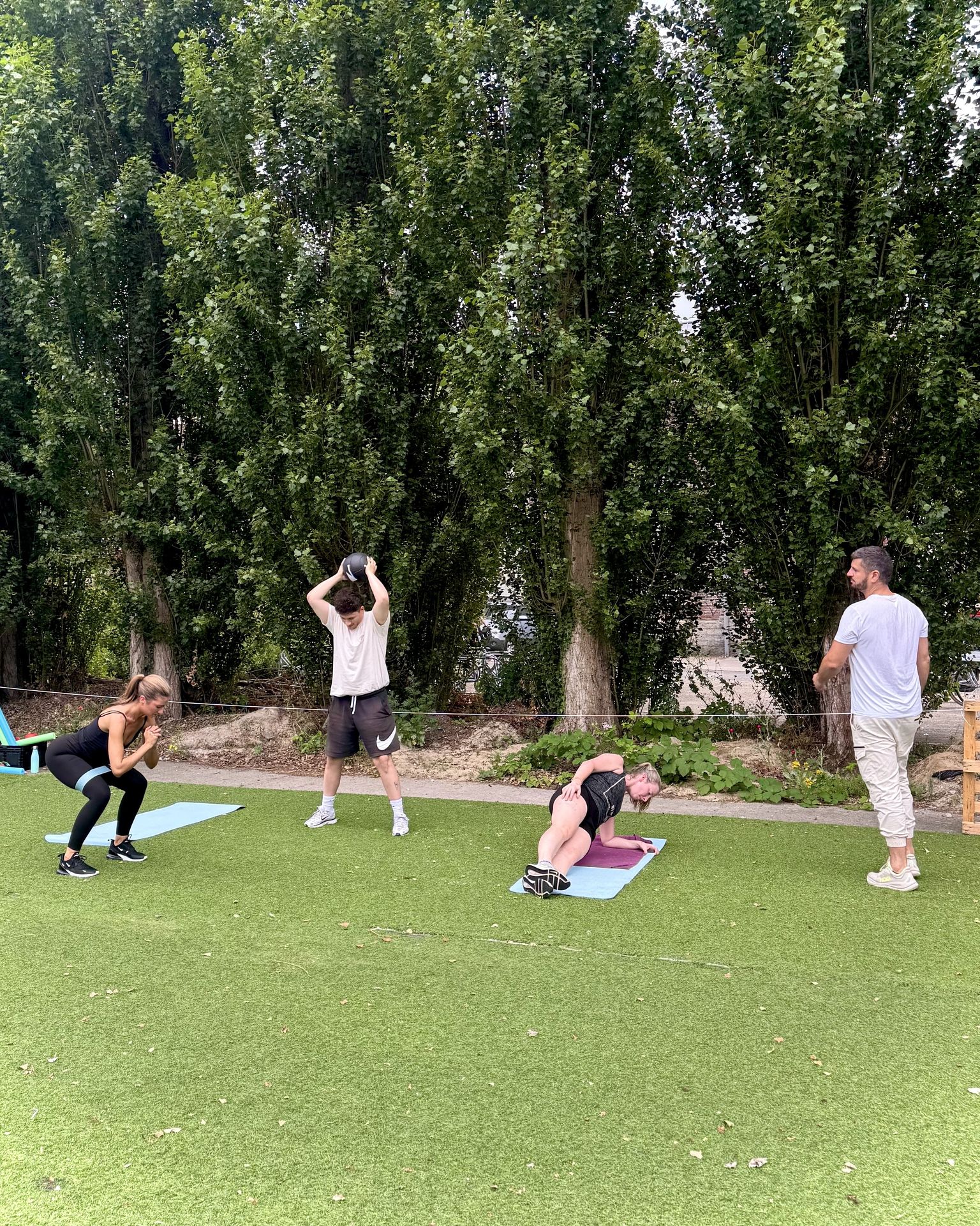 Deelnemers trainen buiten onder de bomen tijdens een outdoor fitnessles van SHOBI Move en Relax
