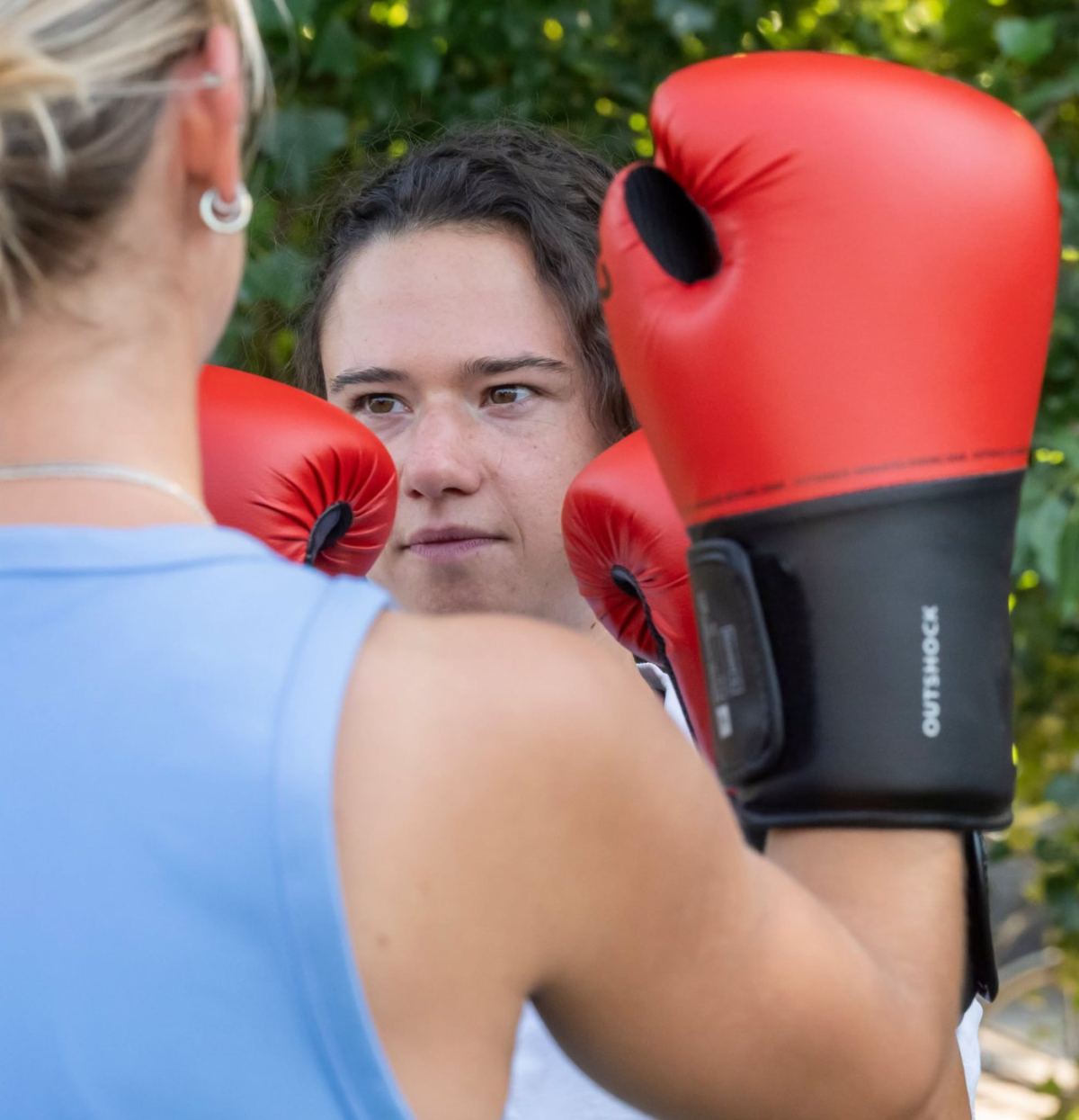 Vrouw houdt haar focus tussen de bokshandschoenen tijdens een boksles voor vrouwen in Gent