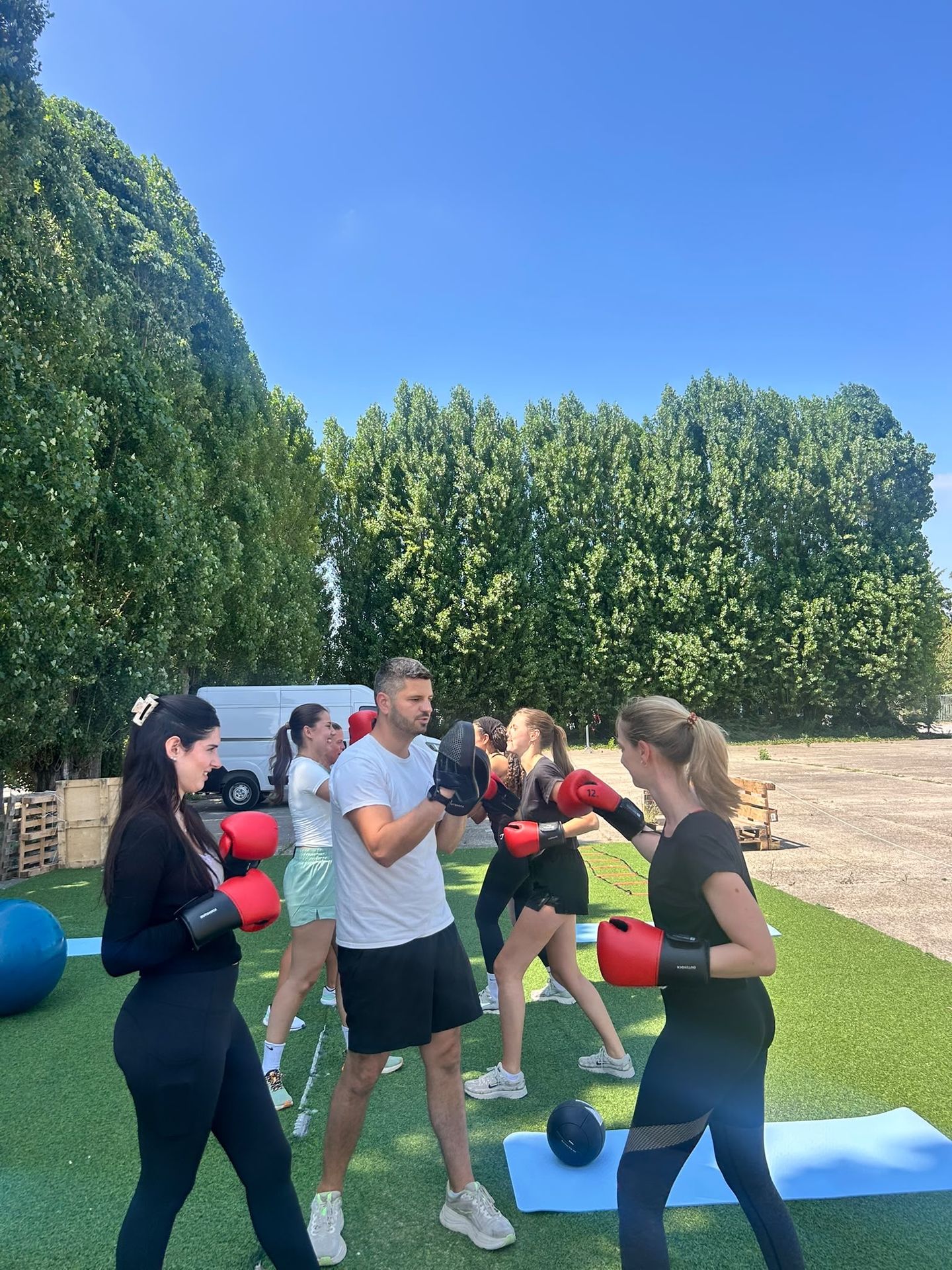 Groep sporters met bokshandschoenen tijdens een outdoor training van SHOBI Move en Relax