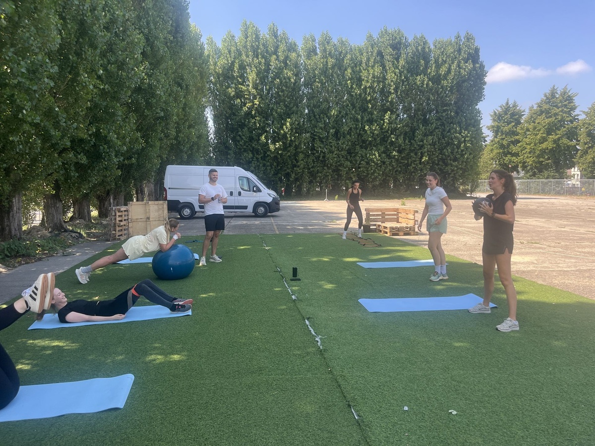 Kleine groep doet core-oefeningen op matjes terwijl de personal trainer meekijkt in Gentbrugge